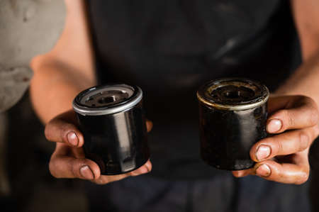 An auto mechanic holds a new and used oil filter.の写真素材