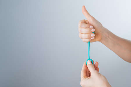 A faceless woman demonstrates a mint-colored vaginal ball. Girl holding a kegel trainer for training pelvic floor muscles on a white background.の写真素材
