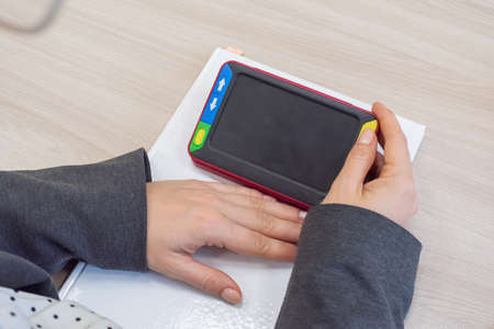 The woman is holding a reading device for the visually impaired. Electronic magnifier for the...