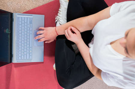 A chubby young woman is watching an online fitness lesson on a laptop. Distance sports training.の写真素材