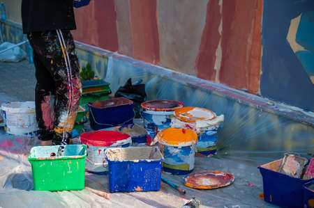 A street artist paints on the wall. close-up of paint buckets.の写真素材