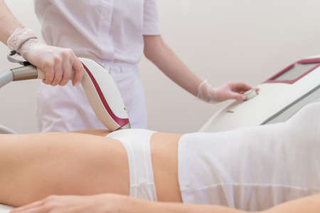A woman in a professional beauty salon removes unwanted vegetation in the bikini area using laser hair removalの写真素材
