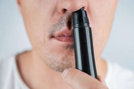 A man cuts his nose hair with a pocket trimmerの写真素材