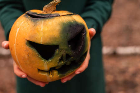A witch holds a creepy pumpkin in a dense autumn forest. Jack o lantern for halloweenの写真素材