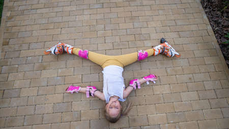 Little girl learns to roller skate and falls. View from above