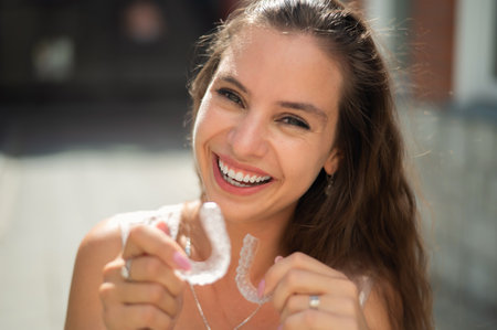 Beautiful caucasian woman holding transparent mouth guards for bite correction.の写真素材