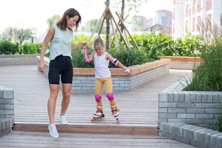 Caucasian woman teaches her daughter to skate on roller skates.の写真素材
