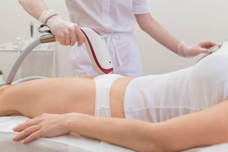 A woman in a professional beauty salon removes unwanted vegetation in the bikini area using laser hair removalの写真素材