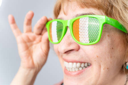 Portrait of smiling elderly woman wearing glasses with ireland flag.