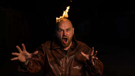 Bald man in a leather jacket with a hot head on a dark background.の写真素材