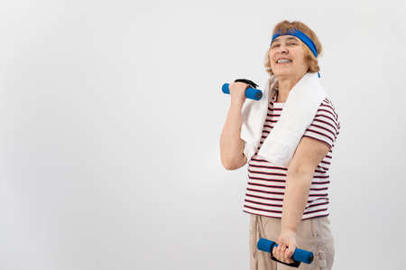 An elderly woman with a blue bandage on her head trains with dumbbells on a white backgroundの写真素材