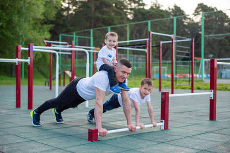 Caucasian man goes in for sports on the sports ground with his sons.の写真素材