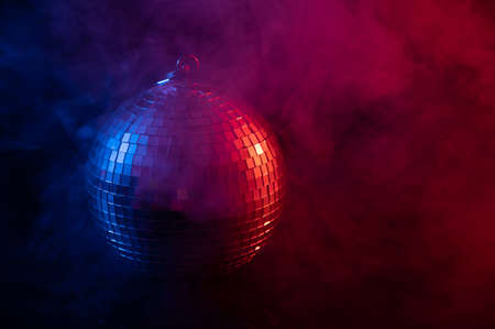 The disco ball is spinning in pink-blue smoke. Night life.の写真素材