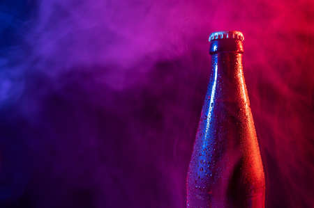 Glass bottle of beer in blue pink mistの写真素材