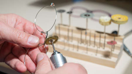 An optician technician polishes the frame of glasses. A professional optician fixes glasses.