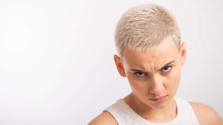 Displeased young caucasian woman with short haircut on white background.の写真素材