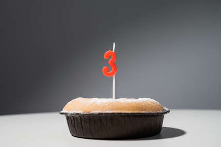 small cake with a candle in the shape of the number three for birthday.の写真素材