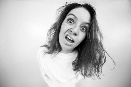Close-up portrait of insane woman in straitjacket on white background. Monochrome.