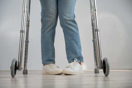 Close-up of female legs with walkers. The girl walks with the help of special equipment.
