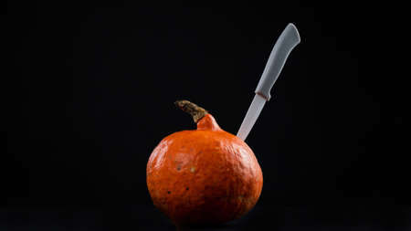 Knife in a pumpkin on a black background. Halloween symbol. Isolate.の写真素材