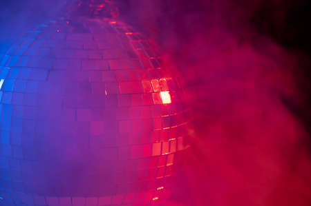 The disco ball is spinning in pink-blue smoke. Night life.