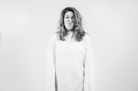 Close-up portrait of insane woman in straitjacket on white background. Monochrome.の写真素材