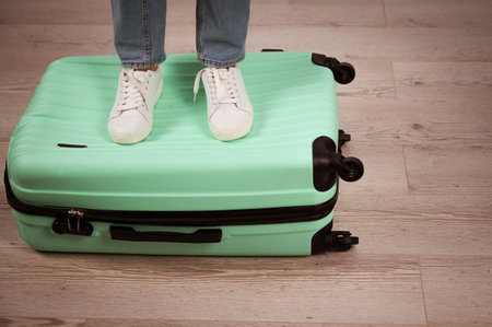 Woman standing with her feet on a suitcase.