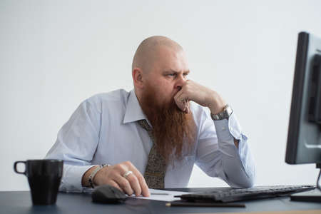 Problems for the office worker. A bald man in a white shirt sits at a desk with a computer and is stressed because of failure. A nervous breakdown.の写真素材