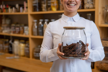 A woman holds croutons in a glass jar. Eco shop without plastic waste.の写真素材
