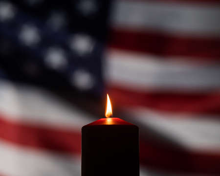 Burning candle against the background of the waving flag of the united states of america in the dark.の写真素材
