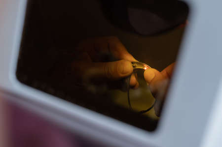 The technician solders the metal frame of the glasses.