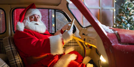 Portrait of santa claus driving a red car for christmas.の写真素材