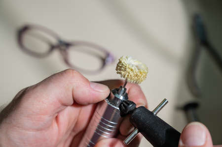 An optician technician polishes the frame of glasses. A professional optician fixes glasses.の写真素材
