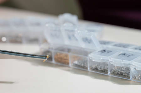 A close-up of male hands takes a screw for repairing glasses with tweezers