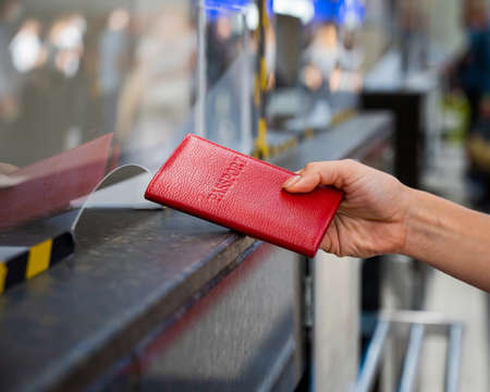 Faceless woman giving her passport at the airport check-in counter.の写真素材