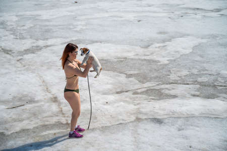 A woman in a bikini walks with a dog in the snowの写真素材