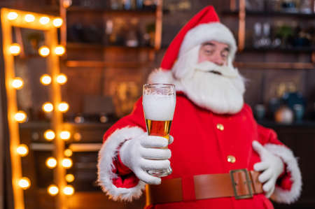 Santa Claus drinks beer while sitting in a leather armchairの写真素材