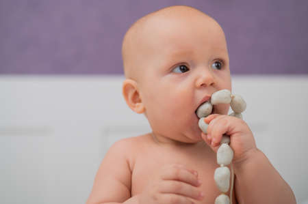 Baby boy gnaws wooden teething boxes. Eco friendly toy.