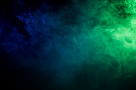 Green-blue smoke in neon light on black background.の写真素材