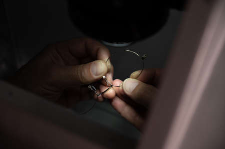 The technician solders the metal frame of the glasses.