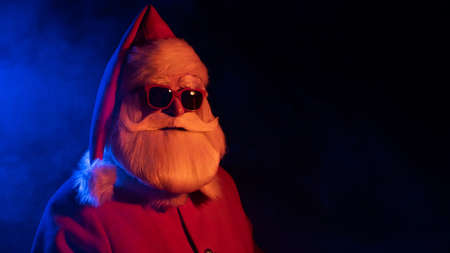 Santa claus in sunglasses in neon light on a black background. Christmas party.