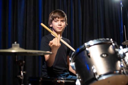 A boy plays drums in a recording studio