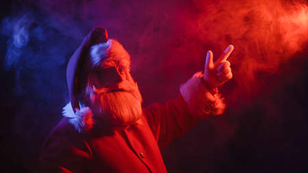 Santa claus in neon light on a black background. Christmas party.の写真素材