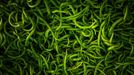 Close-up on a shelf with green peppers in the market.の写真素材