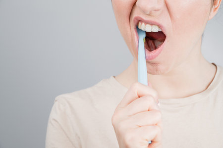 Close-up portrait of caucasian woman brushing her teeth. The girl performs the morning oral hygiene procedureの写真素材
