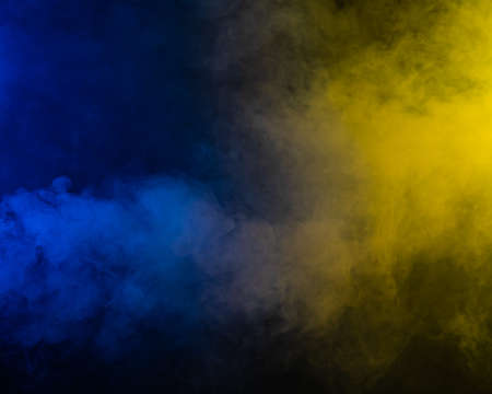 Yellow-blue smoke in neon light on black background.の写真素材