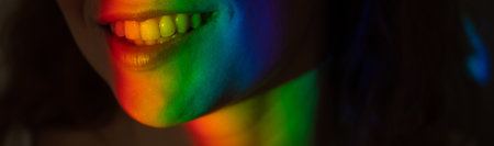 Close-up portrait of smiling woman with ray of rainbow light on her face.の写真素材