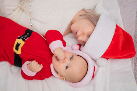 Caucasian woman hugging baby son in santa claus costume.の写真素材