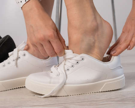 Close-up business woman takes off her shoes puts on white leather sneakers.