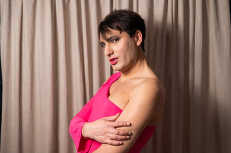 Homosexual in a pink female dress. A man in make-up.